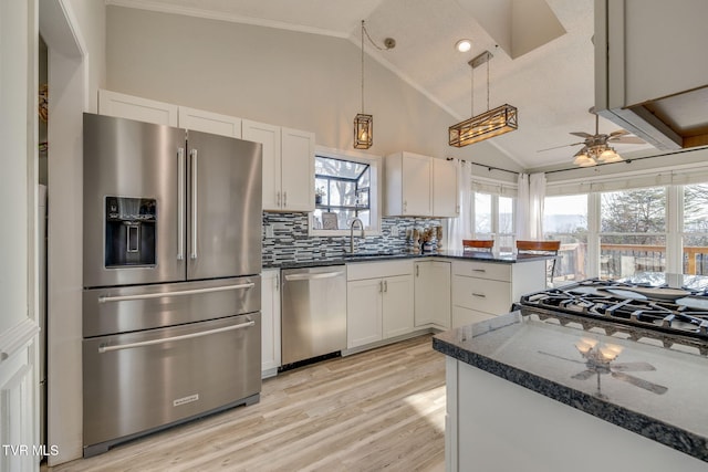 kitchen with dark stone countertops, decorative backsplash, white cabinets, and appliances with stainless steel finishes