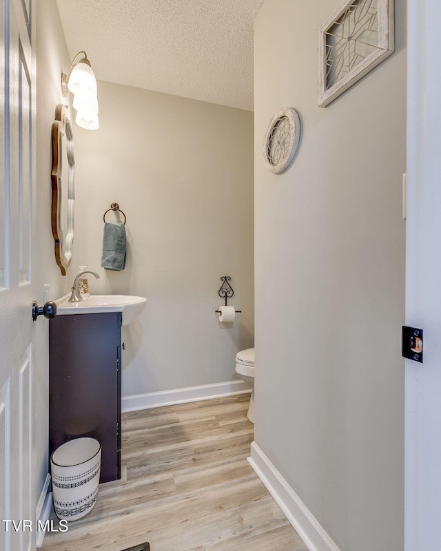 bathroom featuring vanity, wood-type flooring, a textured ceiling, and toilet