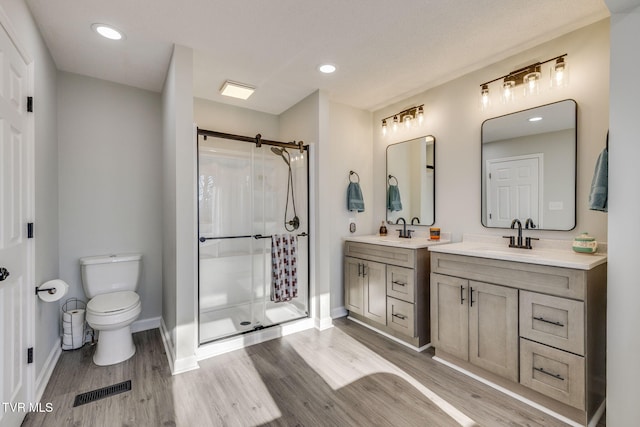 bathroom with vanity, wood-type flooring, a shower with door, and toilet