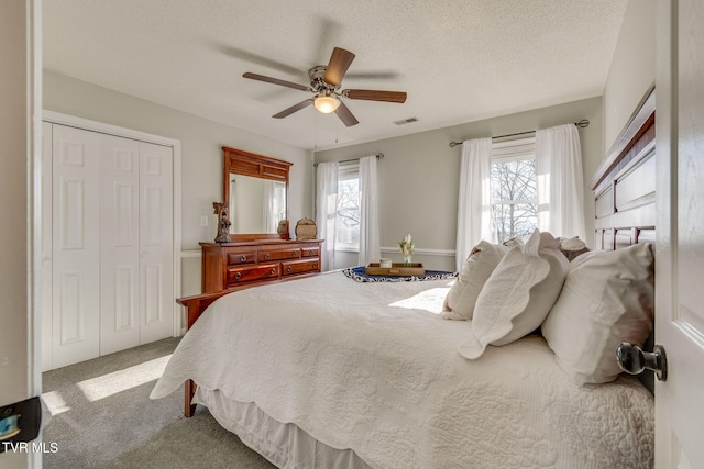 bedroom with ceiling fan, carpet floors, a closet, and a textured ceiling