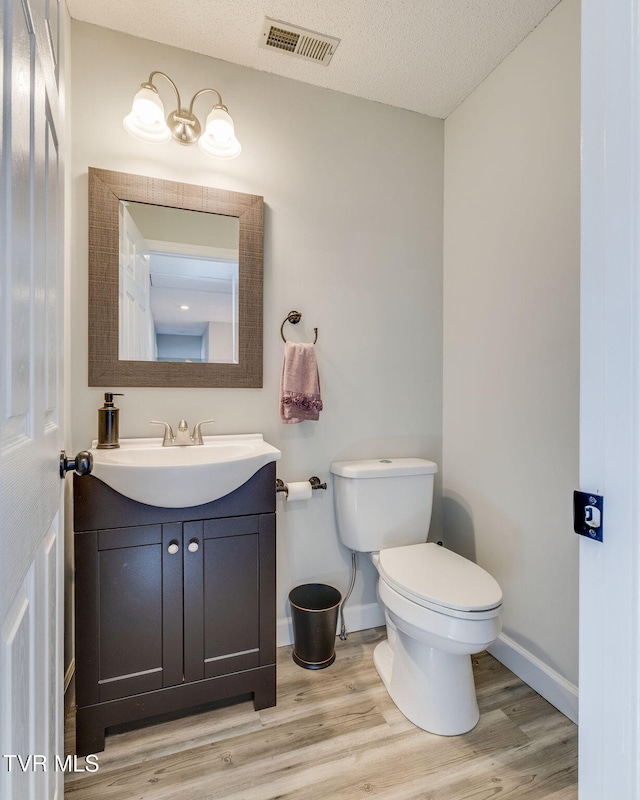 bathroom featuring vanity, hardwood / wood-style flooring, toilet, and a textured ceiling