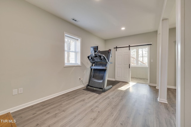 workout room featuring light hardwood / wood-style floors and a barn door