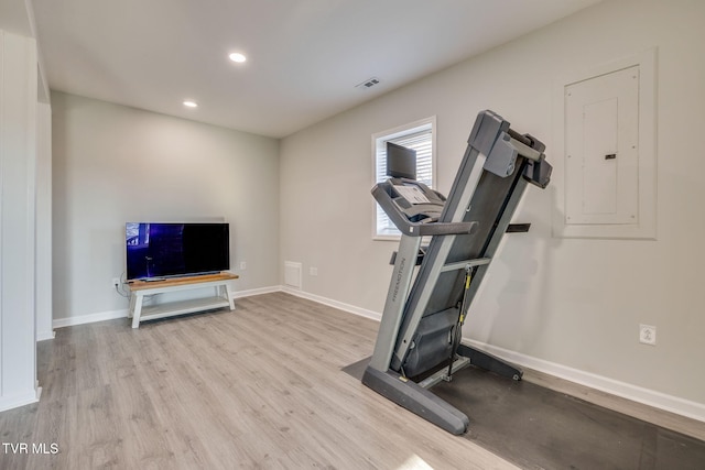 exercise area with electric panel and light hardwood / wood-style floors