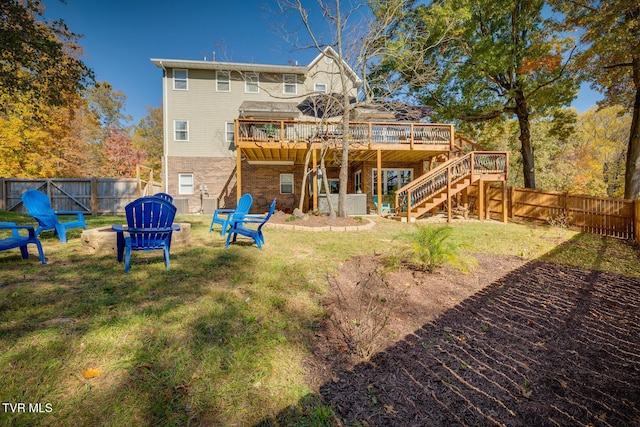 rear view of property with a yard, a deck, and a fire pit