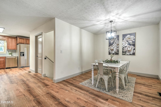 dining area featuring an inviting chandelier, wood-type flooring, and a textured ceiling