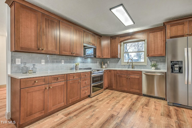 kitchen with tasteful backsplash, stainless steel appliances, light hardwood / wood-style floors, and sink