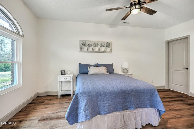 bedroom with ceiling fan, dark hardwood / wood-style flooring, and a textured ceiling