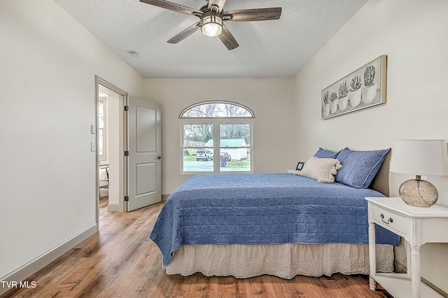 bedroom with ceiling fan, a textured ceiling, and light hardwood / wood-style flooring