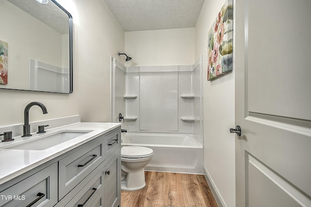 full bathroom featuring vanity, wood-type flooring, a textured ceiling, shower / bathtub combination, and toilet