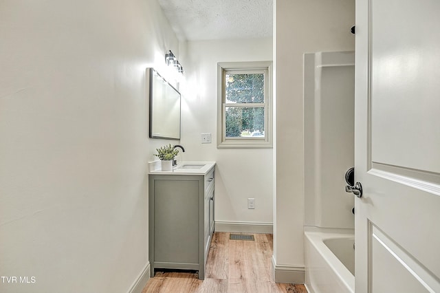 bathroom featuring hardwood / wood-style flooring, vanity, and a textured ceiling