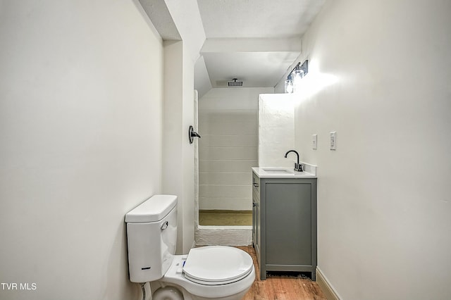 bathroom featuring vanity, wood-type flooring, walk in shower, and toilet