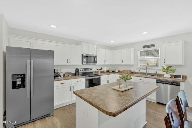 kitchen featuring stainless steel appliances, sink, a kitchen island, and white cabinets