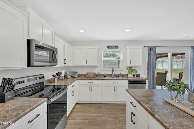 kitchen featuring sink, light hardwood / wood-style flooring, white cabinets, and appliances with stainless steel finishes