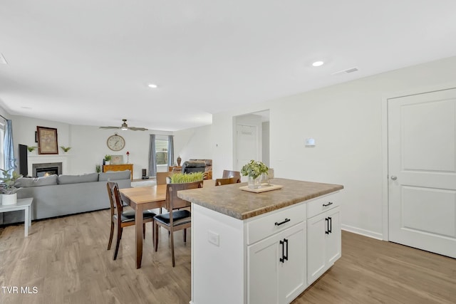 kitchen with white cabinetry, ceiling fan, a center island, and light hardwood / wood-style flooring