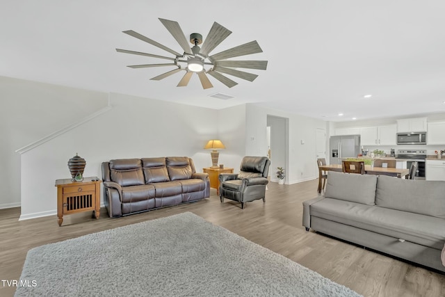 living room with ceiling fan and light hardwood / wood-style flooring