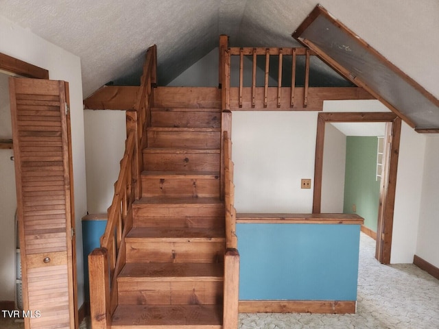 stairs with lofted ceiling, carpet flooring, and a textured ceiling