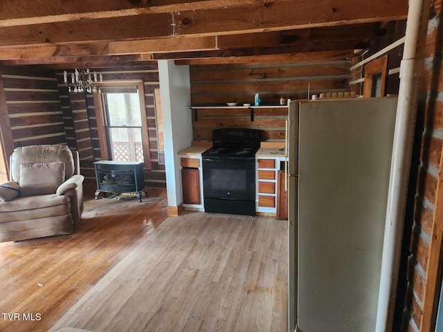 kitchen featuring wooden walls, a wood stove, hardwood / wood-style flooring, white fridge, and electric range