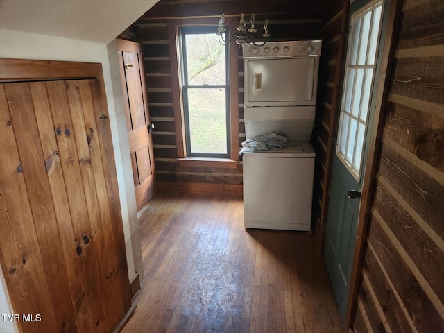 washroom with stacked washer and clothes dryer, a notable chandelier, and dark hardwood / wood-style flooring