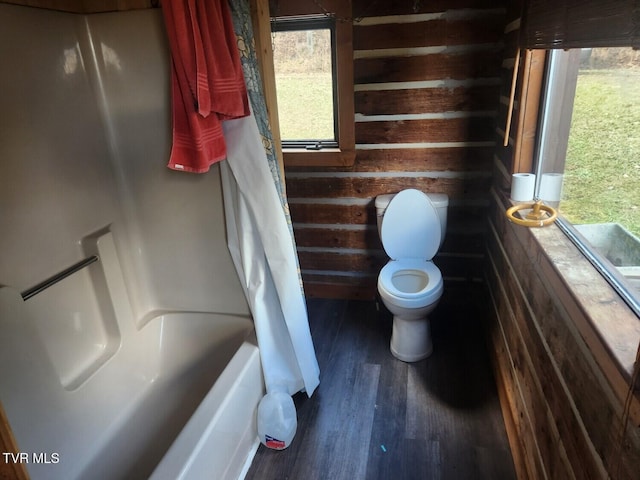 bathroom featuring hardwood / wood-style flooring, shower / bath combo with shower curtain, and toilet