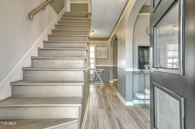 stairs featuring hardwood / wood-style floors and a textured ceiling