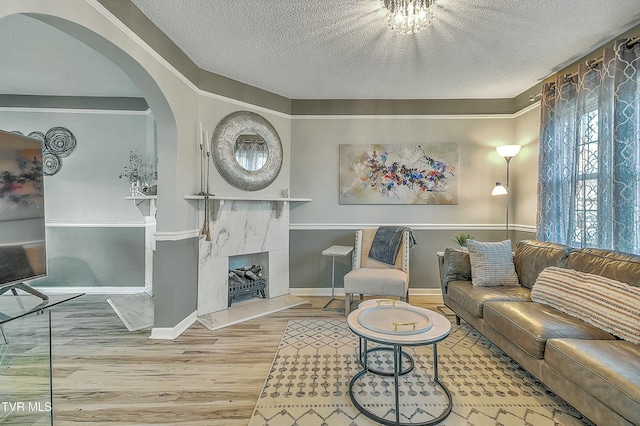 living room with wood-type flooring, a textured ceiling, and a high end fireplace