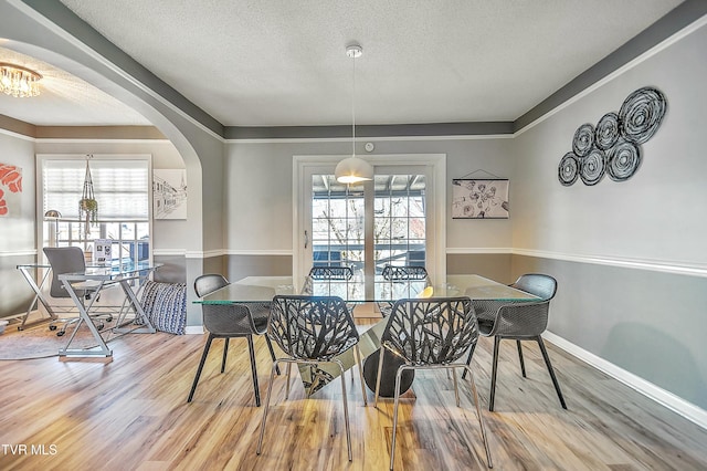 dining room featuring wood-type flooring, a textured ceiling, and a wealth of natural light