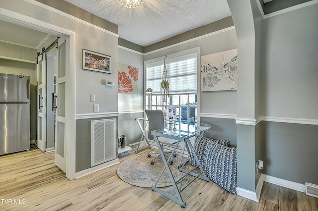 office space with ornamental molding, a barn door, hardwood / wood-style floors, and a textured ceiling