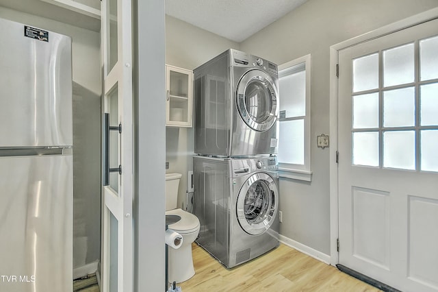 washroom with stacked washer / drying machine and light wood-type flooring