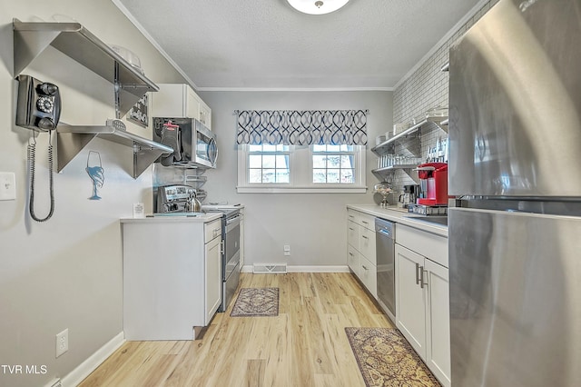 kitchen with white cabinetry, light hardwood / wood-style floors, stainless steel appliances, crown molding, and a textured ceiling