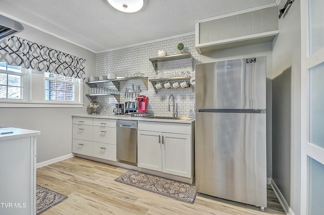 kitchen featuring sink, white cabinetry, light hardwood / wood-style flooring, a textured ceiling, and appliances with stainless steel finishes