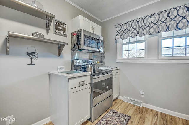 kitchen featuring white cabinetry, appliances with stainless steel finishes, crown molding, and light wood-type flooring