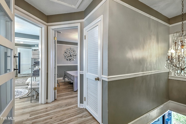 hallway with light hardwood / wood-style floors and a textured ceiling