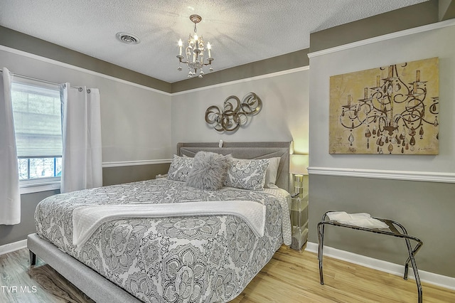 bedroom with a textured ceiling, wood-type flooring, and a chandelier