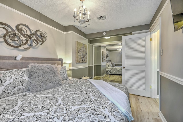 bedroom featuring a notable chandelier, light hardwood / wood-style flooring, a closet, and a textured ceiling