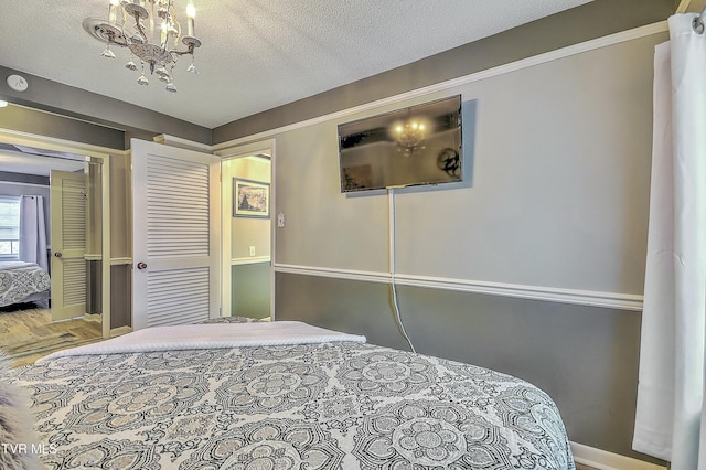 bedroom with an inviting chandelier, wood-type flooring, a closet, and a textured ceiling