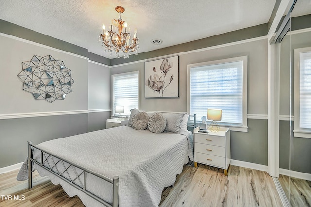 bedroom featuring a chandelier, light hardwood / wood-style flooring, and a textured ceiling