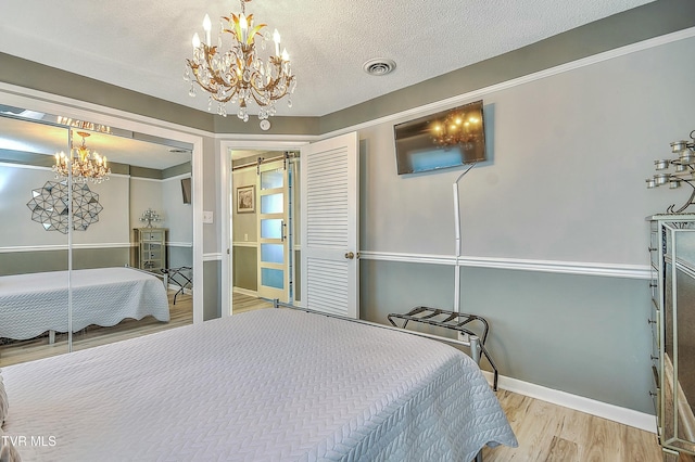 bedroom featuring an inviting chandelier, a closet, light hardwood / wood-style flooring, and a textured ceiling