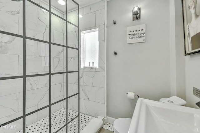 bathroom featuring a tile shower, sink, and toilet