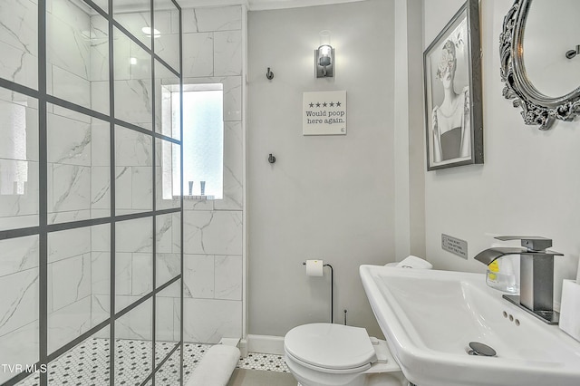 bathroom featuring a tile shower, sink, and toilet