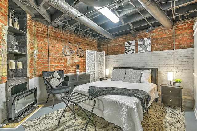 bedroom with brick wall, concrete flooring, and a wood stove