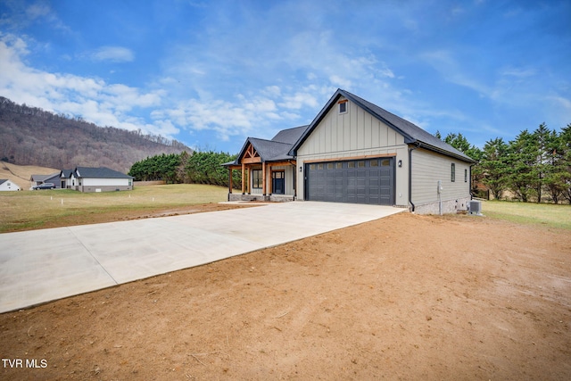 view of front of house with cooling unit, a front yard, covered porch, a mountain view, and a garage