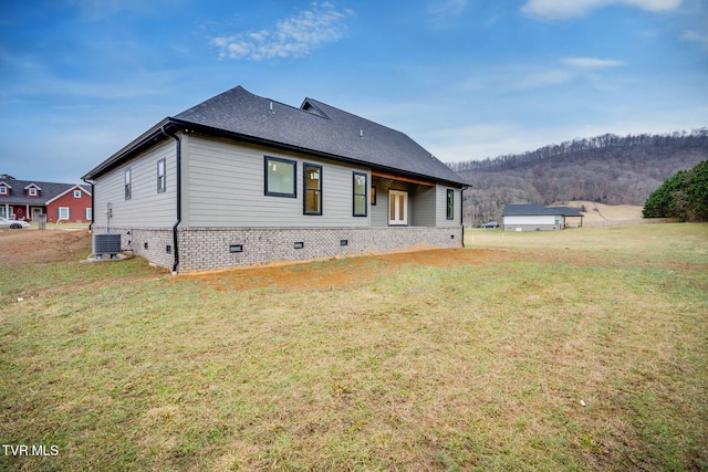 back of property with central AC unit and a yard