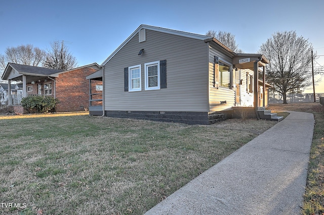 property exterior at dusk with covered porch and a lawn