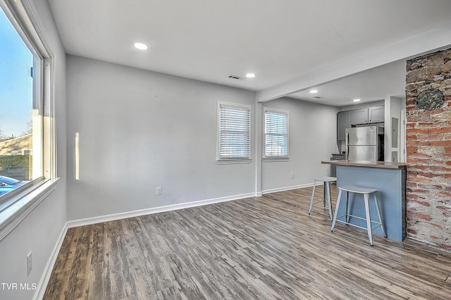 kitchen with dark hardwood / wood-style flooring, stainless steel fridge, a breakfast bar area, and gray cabinets