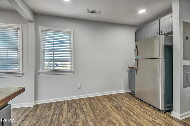 kitchen featuring dark wood-type flooring, gray cabinetry, stainless steel fridge, and electric panel