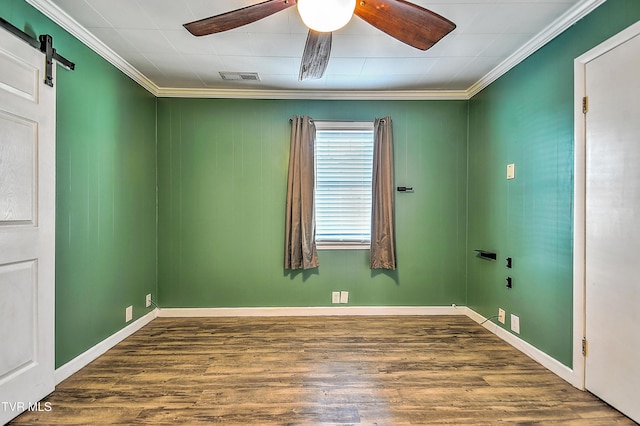 unfurnished room featuring ornamental molding, a barn door, dark wood-type flooring, and ceiling fan