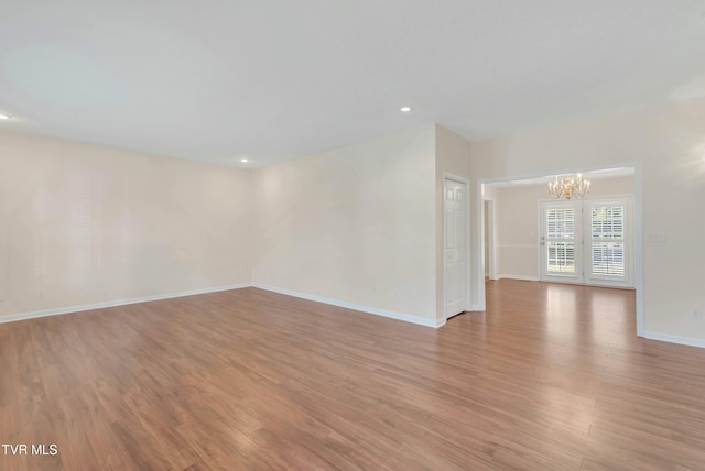 unfurnished room featuring a notable chandelier and light hardwood / wood-style floors