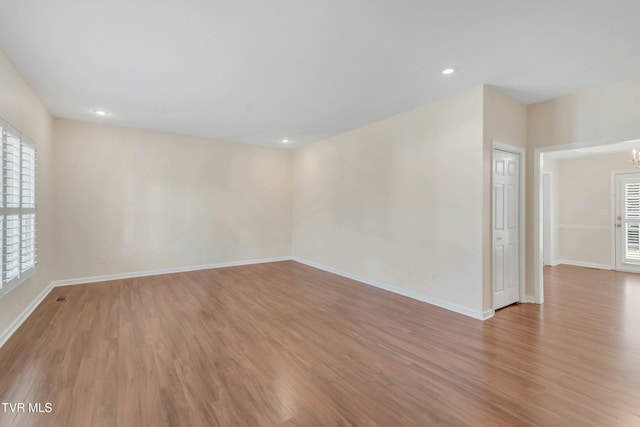 unfurnished room featuring an inviting chandelier, a wealth of natural light, and light hardwood / wood-style flooring