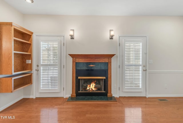 unfurnished living room with hardwood / wood-style flooring and a tile fireplace