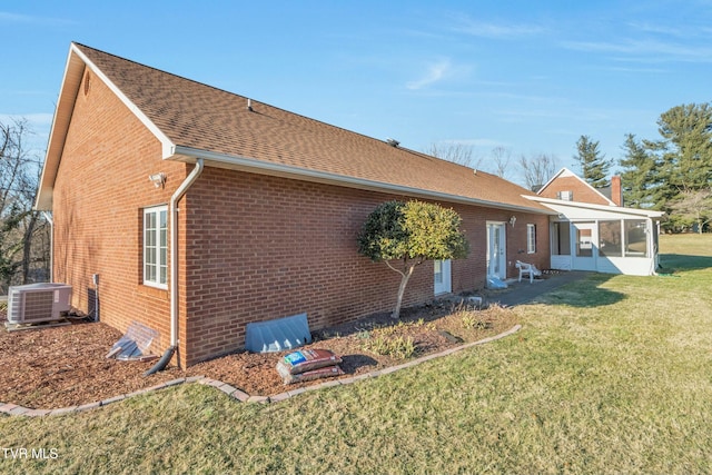 view of side of home with a lawn, a sunroom, and central air condition unit